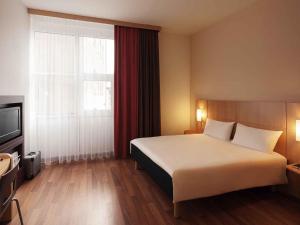 a hotel room with a bed and a large window at ibis Hotel Nürnberg Altstadt in Nuremberg