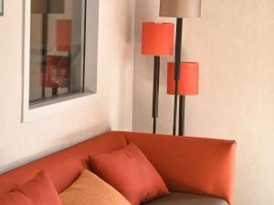 an orange couch in a room with two lamps at ibis Chateauroux in Châteauroux