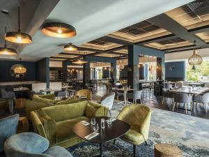 a restaurant with couches and tables and a bar at Mercure Lille Marcq en Baroeul in Marcq-en-Baroeul