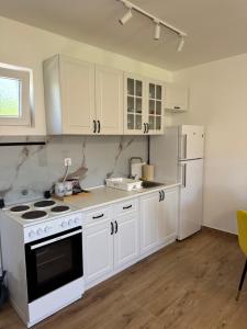 a kitchen with white cabinets and a stove and refrigerator at Magic Home Cetinje in Cetinje +9 photos