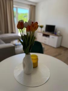 a white vase with red and white flowers on a table at Magic Home Cetinje in Cetinje