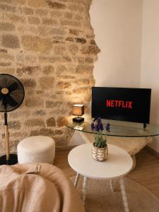 a living room with a table with a netflix sign on a wall at Duplex Le Doux Rêve in Dole