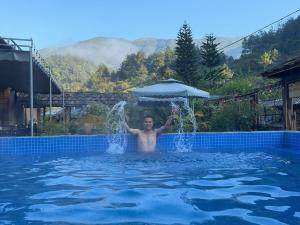 a man in a swimming pool with an umbrella at Nhà Gỗ Cạnh Suối in Bản Det +47 photos