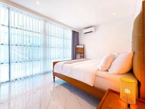 a bedroom with a large bed and large windows at Villa Exquisite Central Seminyak by Nagisa Bali in Seminyak +27 photos