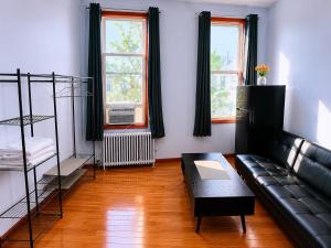 a living room with a black leather couch and two windows at Amazing private Room in Glendale