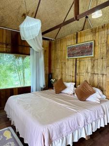a bedroom with a large bed with white sheets at Wanna’s house in Ban Huai Khai
