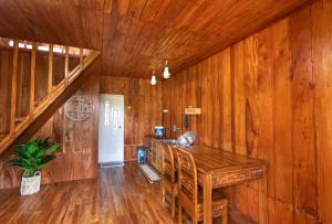 a dining room with wooden walls and a wooden table at Emerald Cabin House in Kejajar