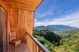 a wooden balcony with a view of the mountains at Emerald Cabin House in Kejajar +16 photos