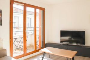 a living room with a tv and a table at Large apartment with balcony - Stade de France in Saint-Denis