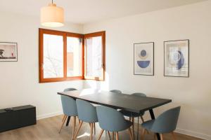 a dining room with a black table and blue chairs at Large apartment with balcony - Stade de France in Saint-Denis