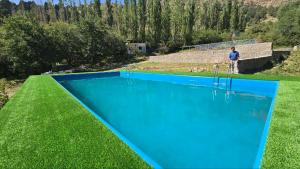 a man standing next to a blue swimming pool at Eagle Rock Nature Stay in Angren