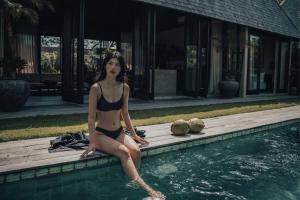 a woman in a bikini sitting in a swimming pool at MIZU Boutique Villas - Unique stay in Uluwatu in Uluwatu