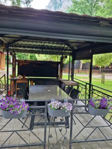 a picnic table under a pavilion with purple flowers at Moravski konak- Moravian Inn in Ovčar Banja