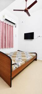 a bed in a room with a ceiling fan at Eden Cozy Villa in Virāmpattinam