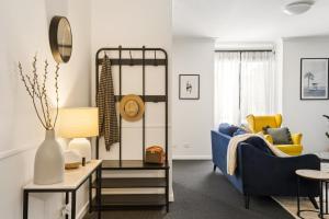 a living room with a blue couch and yellow chairs at OPTUS Stadium 2BR CBD Apartment with FREE Parking in Perth