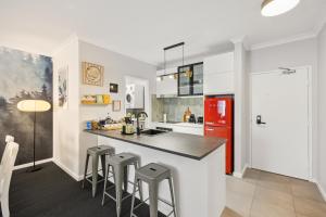 a kitchen with a red refrigerator and bar stools at OPTUS Stadium 2BR CBD Apartment with FREE Parking in Perth