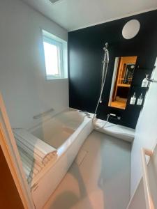 a bathroom with a bath tub and a sink at Hotel Ji ホテル時 in Furano