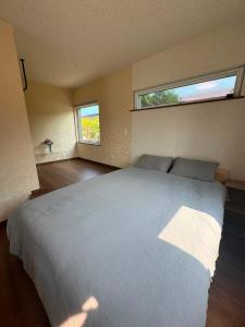 a bedroom with a large white bed with two windows at Hotel Ji ホテル時 in Furano
