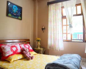 a teddy bear sitting on a bed in a bedroom at Aama Homestay in Kurseong