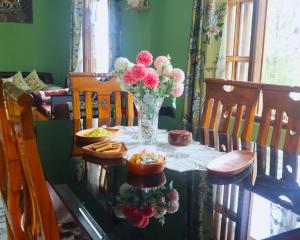 a table with a vase of flowers and snacks at Aama Homestay in Kurseong