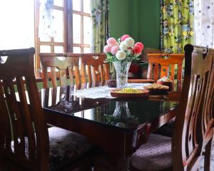 a dining room table with a vase of flowers on it at Aama Homestay in Kurseong +16 photos