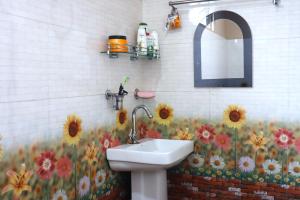 a bathroom with a sink and flowers on the wall at Aama Homestay in Kurseong