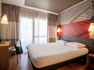 a bedroom with a large white bed and a window at ibis Cannes Plage La Bocca in Cannes