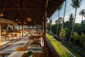 a restaurant with tables and chairs and palm trees at Sarva Ubud Villas & Spa in Ubud