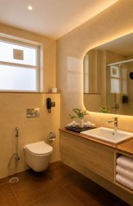 a bathroom with a toilet and a sink and a mirror at Pride Premier Greater Noida in Noida