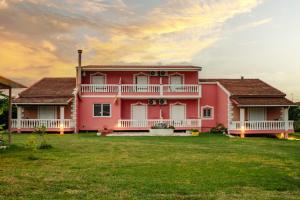 a pink house with a lawn in front of it at Riposo Studios & Apartments in Kavos