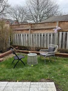 a yard with two chairs and a table and a fence at Home away from home! in Pickering +2 photos