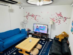 a living room with a blue couch and a tv at 自遊人の宿 in Odawara