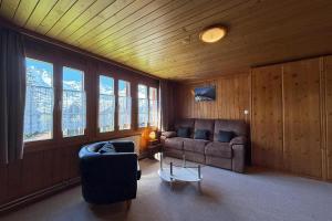 a living room with couches and a table and windows at Chalet Bim Chilchli in Mürren