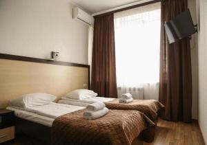 two beds in a hotel room with towels on them at Hotel Koral in Chernivtsi