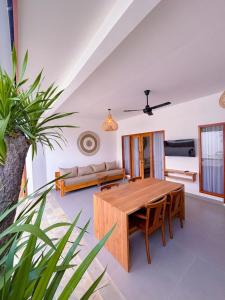 a dining room with a wooden table and a couch at Ajolie Villa in Gili Islands
