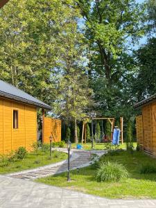 a garden with a yellow house and a playground at Chatka pod orzechem in Spytkowice