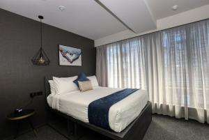 a bedroom with a bed and a large window at The Viv Hotel Wellington in Wellington