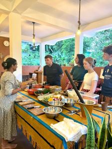 a group of people standing around a table with food at Rest Full Homestay in Ella