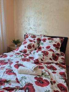 a bed with a floral comforter and two pillows at Makowy Apartament in Milicz