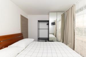 a white bedroom with a bed and a mirror at Villa Kovac in Zadar