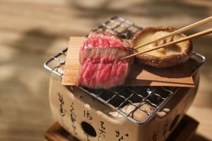 a piece of meat with chopsticks in a basket at Ochiairo in Izu