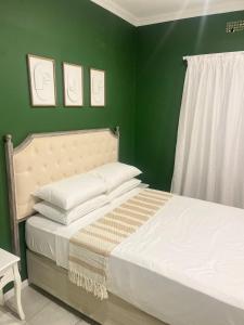 a bedroom with two beds and a green wall at The Residence at 1907 in Thulamahashi