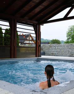 a woman is sitting in a swimming pool at PRZY TERMACH apartamenty, pokoje - podgrzewany basen, hydromasaż i tylko 70m Termy in Szaflary +30 photos