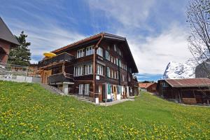 a large wooden house on a hill with a mountain at Chalet Bim Chilchli in Mürren