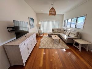 a living room with a couch and a flat screen tv at Cool and Calm - Bring your own linen in South West Rocks