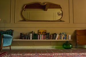 a shelf with books and a mirror on a wall at La Celeste Galeria in Mantova