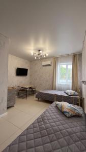 a bedroom with two beds and a table and a television at Эталон АПАРТ-ОТЕЛЬ Aqtobе in Aktobe