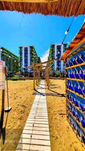 a beach with a straw umbrella and some buildings at Azure in Mamaia Sat/Năvodari