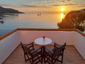 a table and two chairs on a balcony with the sunset at ELEVER Apartments in Agia Marina
