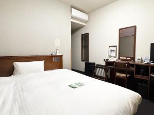 a bedroom with a bed and a desk with a computer at Hotel Route-Inn Isahaya Inter in Isahaya +20 photos